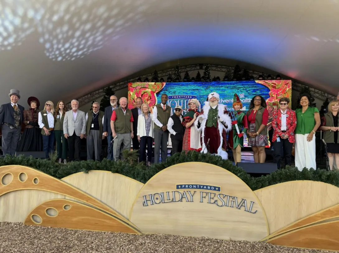 Elected officials, community partners, Mr. and Mrs. Claus, and a festive elf gather for the ribbon-cutting ceremony, officially ushering in the start of the Frontyard Holiday Festival.