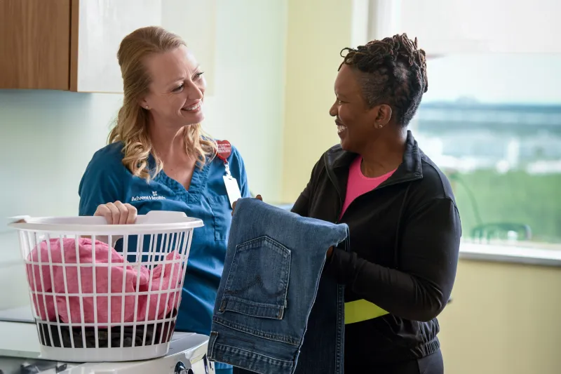A female patient folds laundry with a rehab specialist.