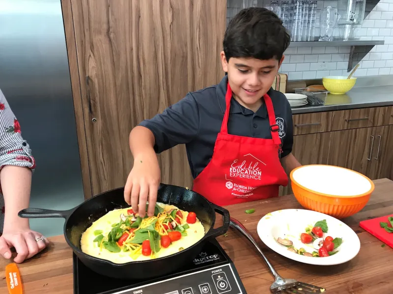 A boy cooks a fajita in a cast-iron pan.