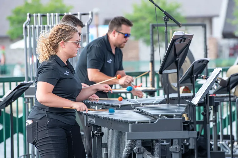 Members of the AdventHealth Orchestra playing mallet percussion instruments while outdoors.