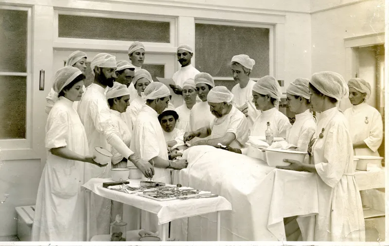 John Harvey Kellogg performing surgery with surgical team and viewers.